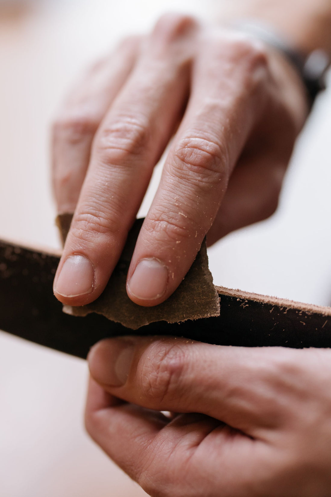 Mani che levigano un listello di legno con carta abrasiva.