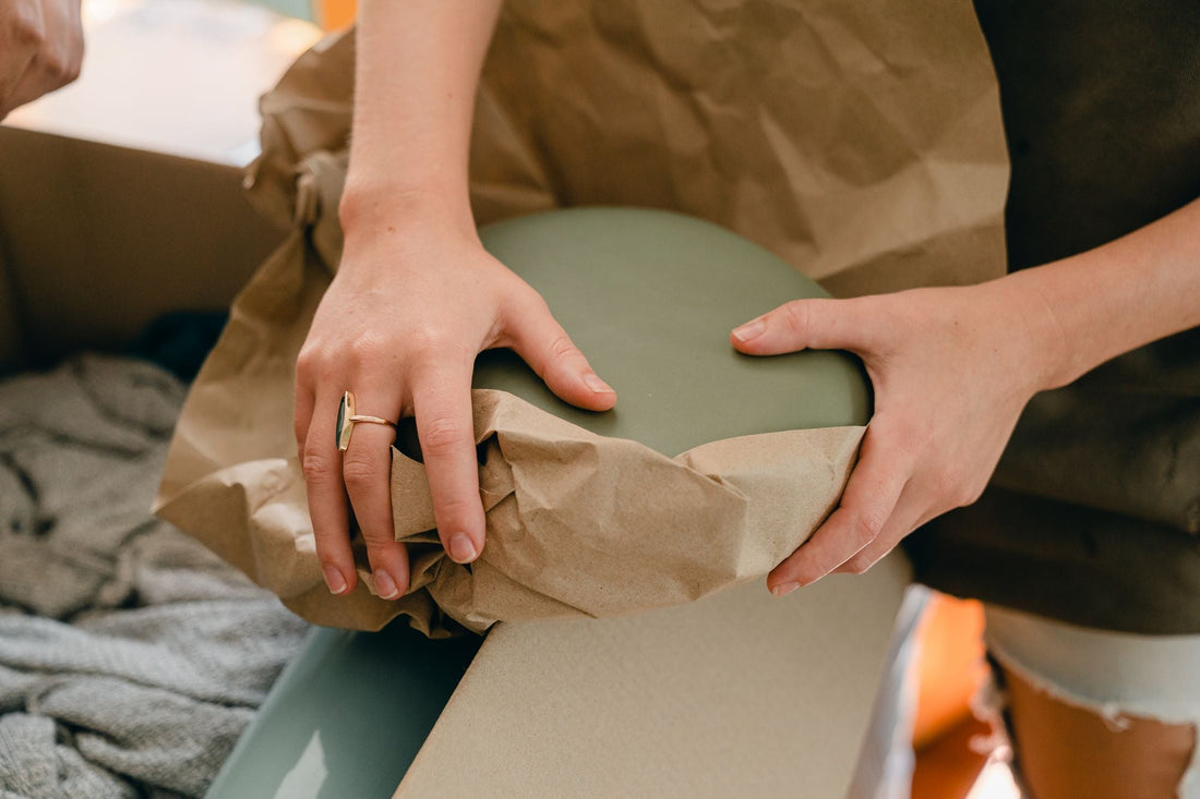Protezione di un oggetto fragile in ceramica con carta da imballaggio prima della spedizione.