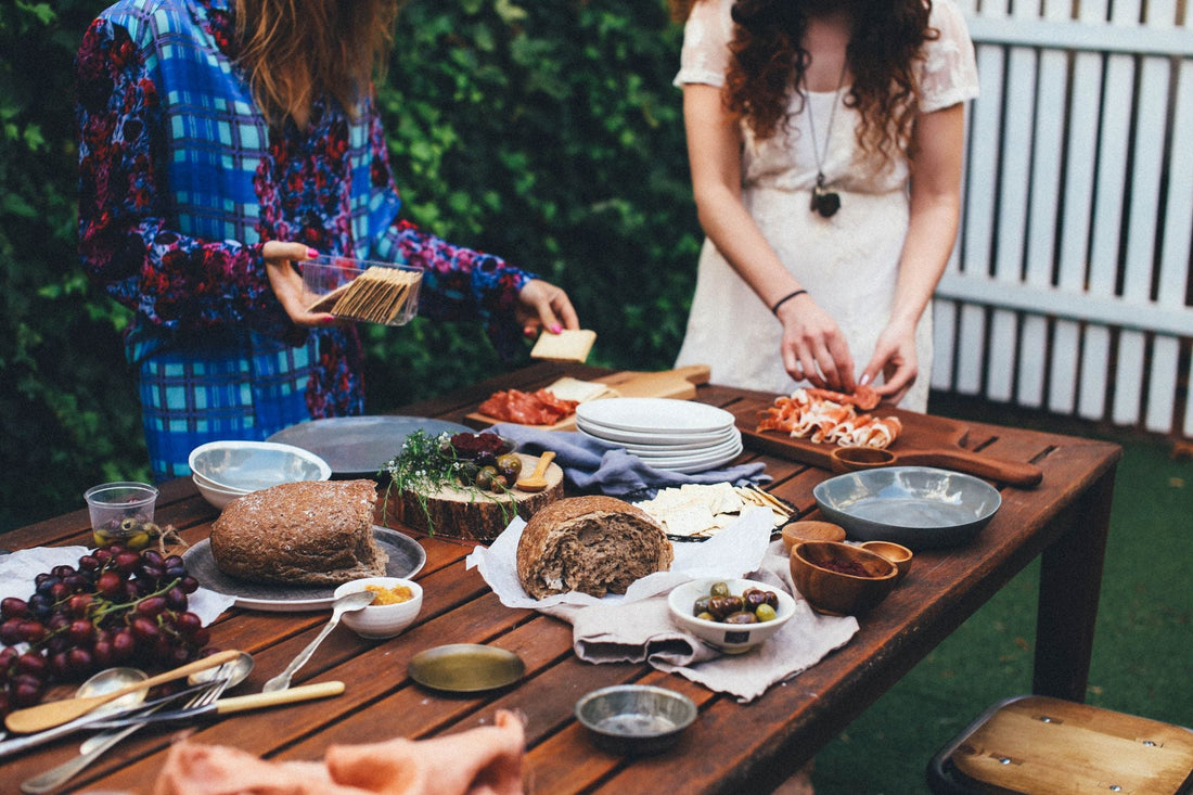 Preparazione di un pranzo in giardino su un tavolo di legno con pane, piatti e ciotole